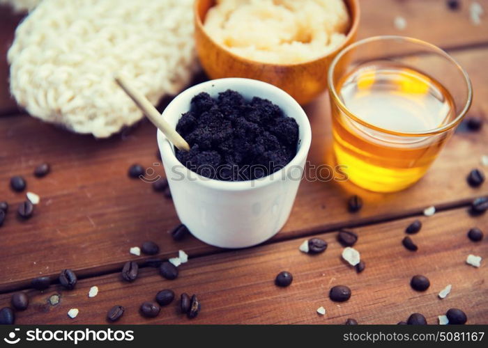 beauty, spa, body care, bath and natural cosmetics concept - close up of coffee scrub in cup and honey on wooden table. close up of coffee scrub in cup and honey on wood