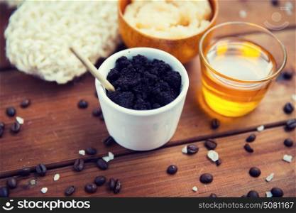 beauty, spa, body care, bath and natural cosmetics concept - close up of coffee scrub in cup and honey on wooden table. close up of coffee scrub in cup and honey on wood