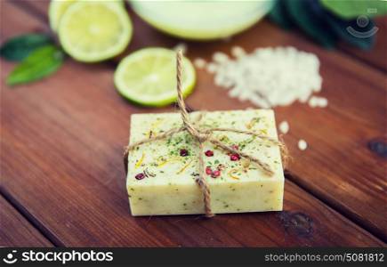 beauty, spa, body care, bath and natural cosmetics concept - close up of handmade herbal soap bar on wooden table. close up of handmade herbal soap bar on wood