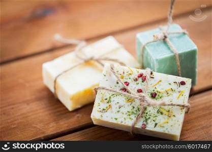 beauty, spa, body care, bath and natural cosmetics concept - close up of handmade soap bars on wooden table