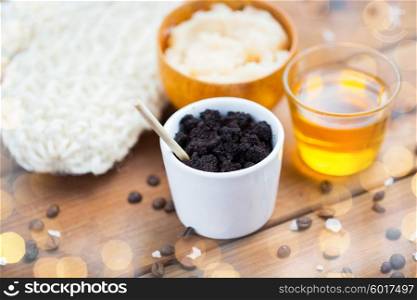 beauty, spa, body care, bath and natural cosmetics concept - close up of coffee scrub in cup and honey on wooden table