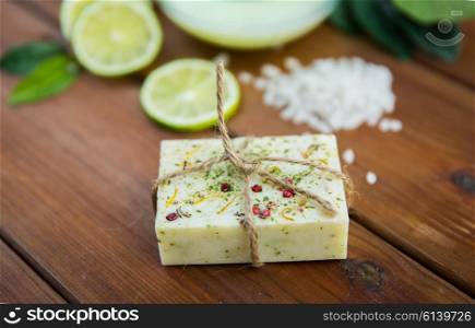 beauty, spa, body care, bath and natural cosmetics concept - close up of handmade herbal soap bar on wooden table