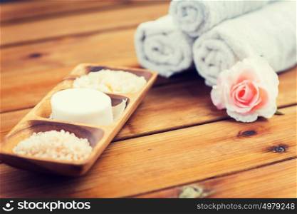 beauty, spa, body care, natural cosmetics and bath concept - close up of soap with himalayan salt and scrub in wooden bowl on table. close up of soap, himalayan salt and scrub in bowl