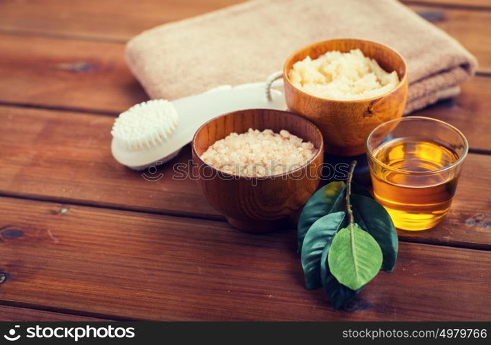 beauty, spa, body care, natural cosmetics and bath concept - close up of himalayan pink salt and body scrub with brush on wooden table. close up of himalayan pink salt and bath stuff