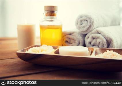 beauty, spa, body care, natural cosmetics and bath concept - close up of soap with himalayan salt and scrub in wooden bowl on table. close up of soap, himalayan salt and scrub in bowl