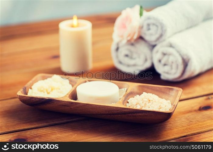 beauty, spa, body care, natural cosmetics and bath concept - close up of soap natural cosmetics himalayan salt and scrub in wooden bowl on table. close up of soap, himalayan salt and scrub in bowl