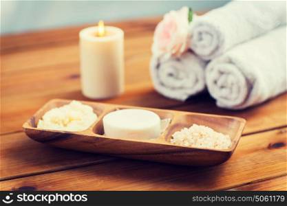 beauty, spa, body care, natural cosmetics and bath concept - close up of soap natural cosmetics himalayan salt and scrub in wooden bowl on table. close up of soap, himalayan salt and scrub in bowl