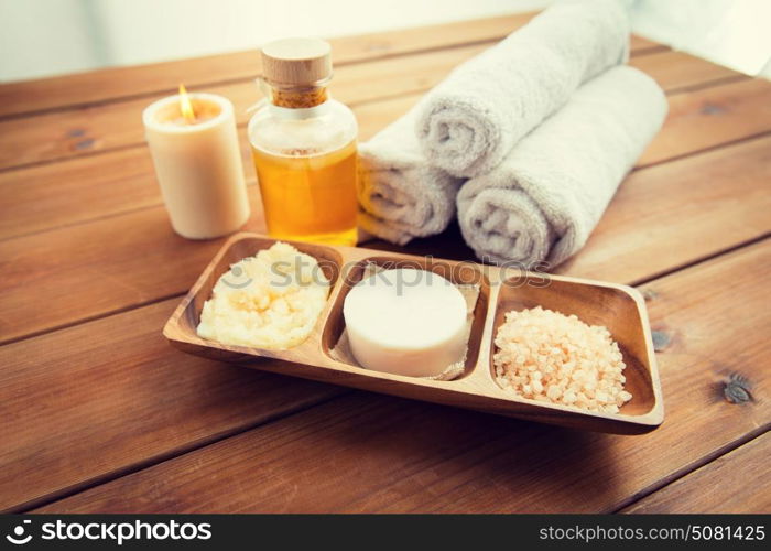 beauty, spa, body care, natural cosmetics and bath concept - close up of soap with himalayan salt and scrub in wooden bowl on table. close up of soap, himalayan salt and scrub in bowl