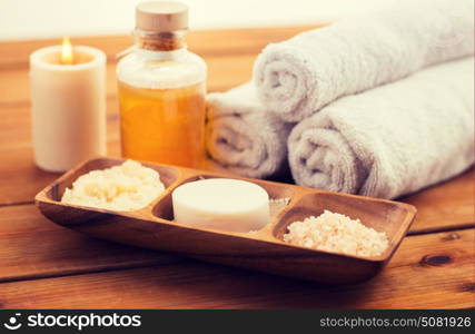 beauty, spa, body care, natural cosmetics and bath concept - close up of soap natural cosmeticshimalayan salt and scrub in wooden bowl on table. close up of soap, himalayan salt and scrub in bowl