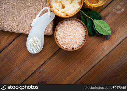 beauty, spa, body care, natural cosmetics and bath concept - close up of himalayan pink salt with brush and towel on wooden table