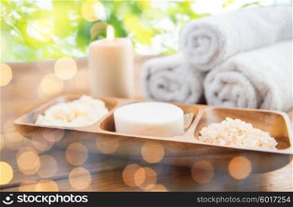 beauty, spa, body care, natural cosmetics and bath concept - close up of soap with himalayan salt and scrub in wooden bowl on table