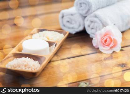 beauty, spa, body care, natural cosmetics and bath concept - close up of soap with himalayan salt and scrub in wooden bowl on table
