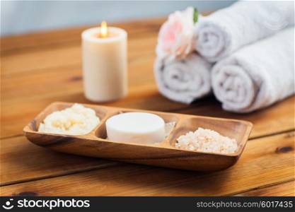 beauty, spa, body care, natural cosmetics and bath concept - close up of soap natural cosmetics himalayan salt and scrub in wooden bowl on table