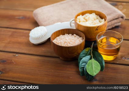 beauty, spa, body care, natural cosmetics and bath concept - close up of himalayan pink salt and body scrub with brush on wooden table