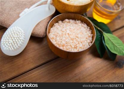 beauty, spa, body care, natural cosmetics and bath concept - close up of himalayan pink salt with brush on wooden table