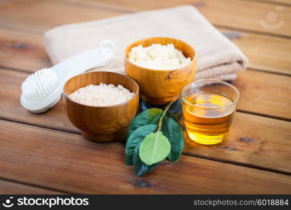beauty, spa, body care, natural cosmetics and bath concept - close up of himalayan pink salt and body scrub with brush on wooden table
