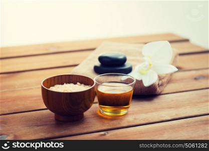 beauty, spa, body care, natural cosmetics and concept - close up of pink salt with honey in glass and bath towel on wooden table. close up of pink salt with honey and bath stuff