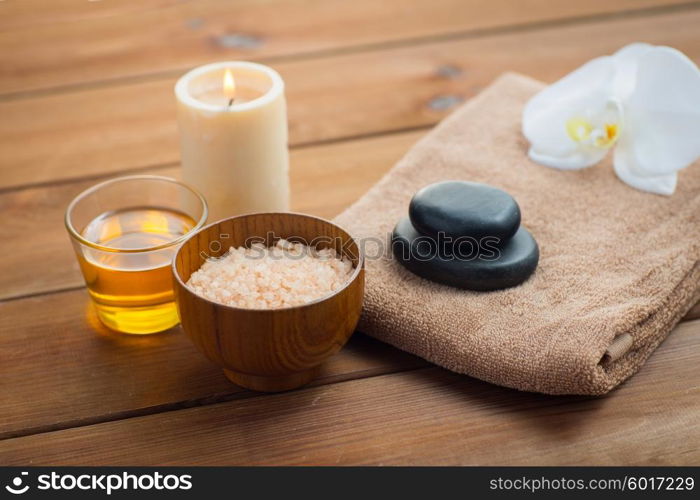 beauty, spa, body care, natural cosmetics and concept - close up of pink salt with honey in glass and bath towel on wooden table