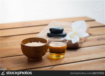 beauty, spa, body care, natural cosmetics and concept - close up of pink salt with honey in glass and bath towel on wooden table