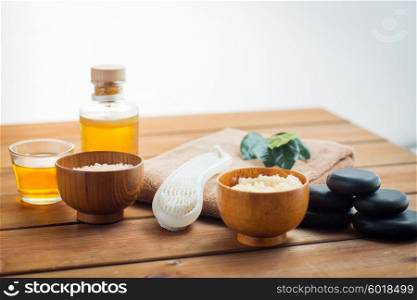 beauty, spa, body care, natural cosmetics and massage concept - close up of body scrub with brush on wooden table