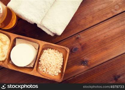 beauty, spa, body care, natural cosmetics and wellness concept - close up of soa with himalayan pink salt and bath towels on wooden table. close up of natural cosmetics and bath towels