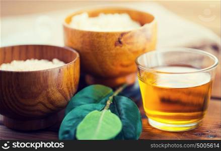beauty, spa, body care, natural cosmetics and wellness concept - close up of honey in glass with leaves on wooden table. close up of honey in glass with leaves on wood