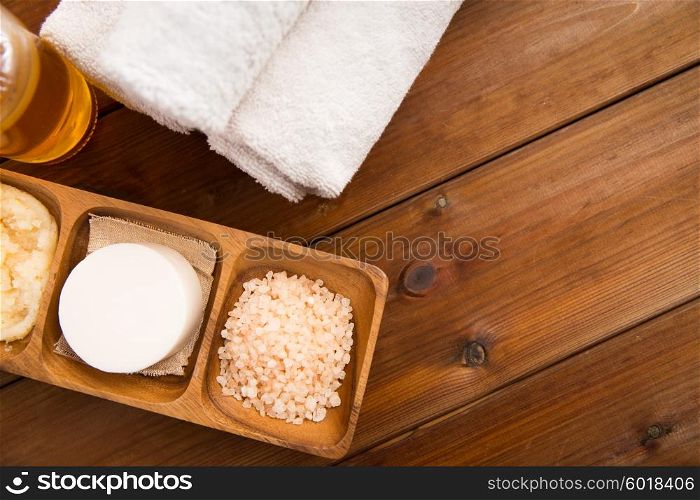 beauty, spa, body care, natural cosmetics and wellness concept - close up of soa with himalayan pink salt and bath towels on wooden table