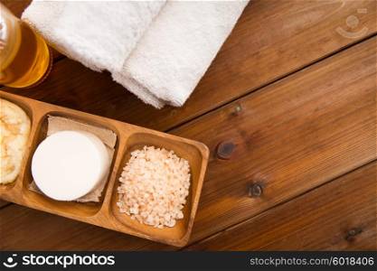 beauty, spa, body care, natural cosmetics and wellness concept - close up of soa with himalayan pink salt and bath towels on wooden table