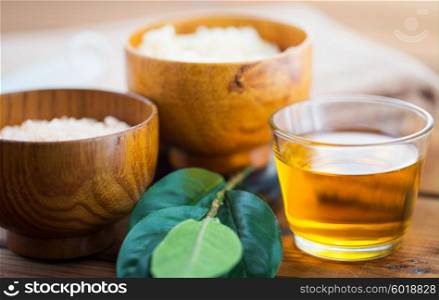 beauty, spa, body care, natural cosmetics and wellness concept - close up of honey in glass with leaves on wooden table
