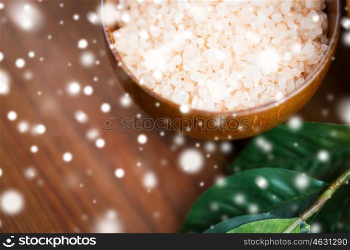 beauty, spa, bodycare, bath and natural cosmetics concept - close up of himalayan pink salt in wooden bowl with leaves over snow