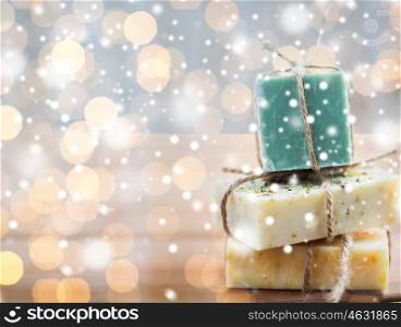 beauty, spa, bodycare, bath and natural cosmetics concept - close up of handmade soap bars over lights and snow