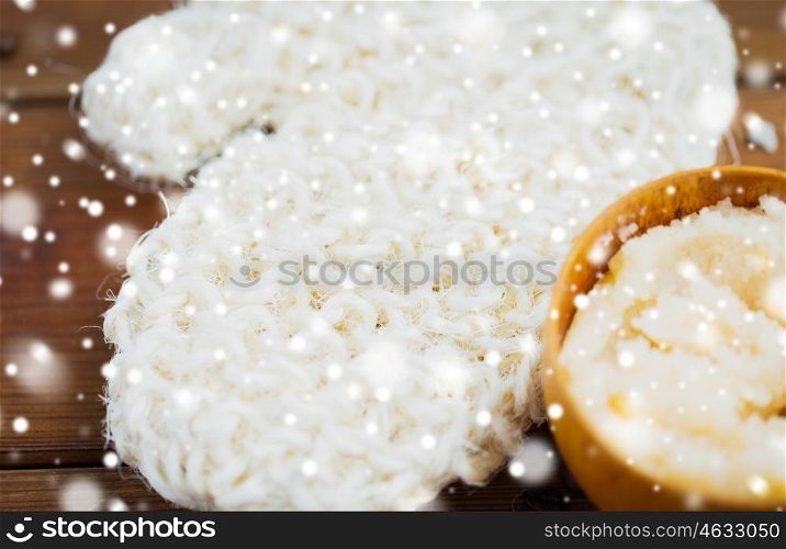 beauty, spa, bodycare, bath and natural cosmetics concept - close up of wisp and body scrub in cup on wooden table over snow