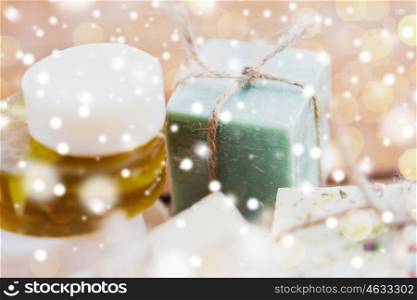 beauty, spa, bodycare, bath and natural cosmetics concept - close up of handmade soap bars over snow