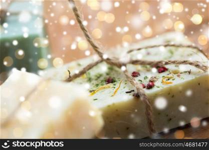 beauty, spa, bodycare, bath and natural cosmetics concept - close up of handmade soap bars over lights and snow