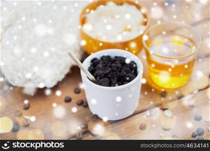 beauty, spa, bodycare, bath and natural cosmetics concept - coffee scrub in cup and honey on wooden table over lights and snow