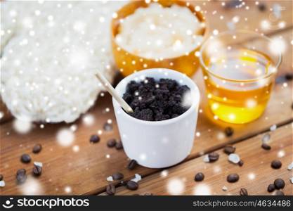 beauty, spa, bodycare, bath and natural cosmetics concept - coffee scrub in cup and honey on wooden table over snow