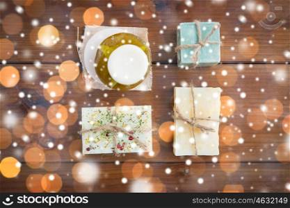 beauty, spa, bodycare, bath and natural cosmetics concept - handmade soap bars on wooden table over lights and snow