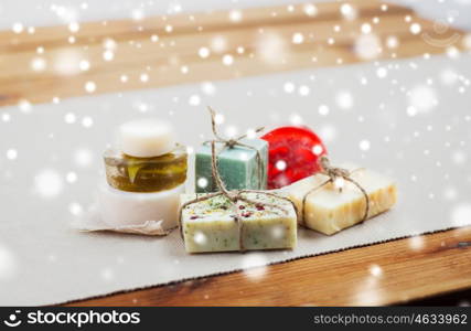 beauty, spa, bodycare, bath and natural cosmetics concept - handmade soap bars on wooden table over snow