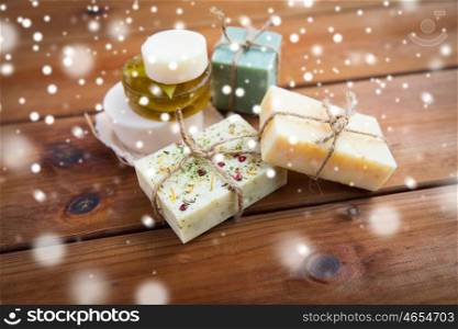 beauty, spa, bodycare, bath and natural cosmetics concept - handmade soap bars on wooden table over snow