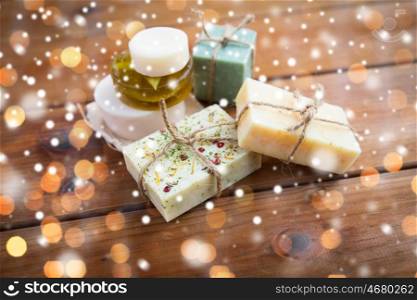 beauty, spa, bodycare, bath and natural cosmetics concept - handmade soap bars on wood over lights and snow