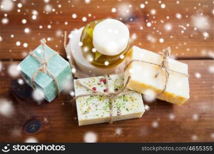 beauty, spa, bodycare, bath and natural cosmetics concept -handmade soap bars on wooden table over snow