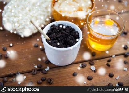 beauty, spa, bodycare, bath and natural cosmetics concept - homemade coffee scrub in cup and honey on wooden table over snow
