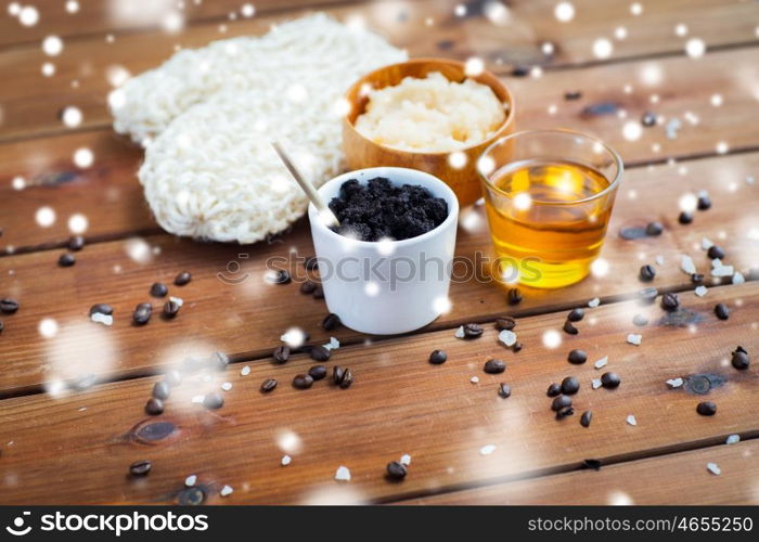 beauty, spa, bodycare, bath and natural cosmetics concept - homemade coffee scrub in cup with wisp and honey on wooden table over snow