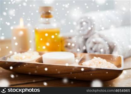 beauty, spa, bodycare, natural cosmetics and bath concept - close up of soap with himalayan salt and scrub in wooden bowl on table over snow