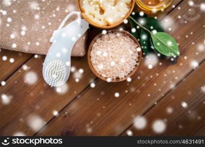 beauty, spa, bodycare, natural cosmetics and bath concept - himalayan pink salt with brush and towel on wooden table over snow