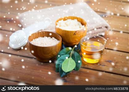 beauty, spa, bodycare, natural cosmetics and bath concept - himalayan pink salt and body scrub with brush and glass of honey on wooden table over snow