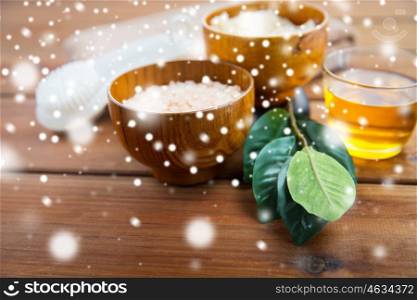 beauty, spa, bodycare, natural cosmetics and bath concept - himalayan pink salt and body scrub with brush on wooden table over snow