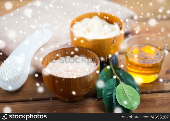 beauty, spa, bodycare, natural cosmetics and bath concept - himalayan pink salt and body scrub with brush on wooden table over snow