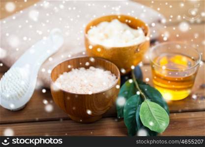 beauty, spa, bodycare, natural cosmetics and bath concept - himalayan pink salt and body scrub with brush on wooden table over snow
