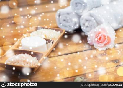 beauty, spa, bodycare, natural cosmetics and bath concept - soap with himalayan salt and scrub in wooden bowl on table over lights and snow